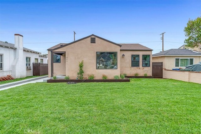 view of front facade with fence, a front lawn, and stucco siding