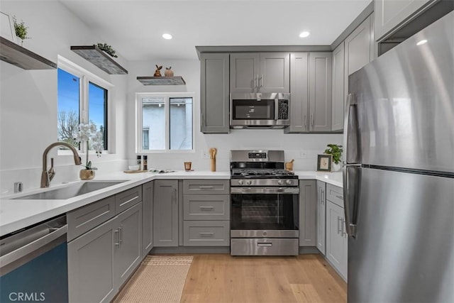 kitchen featuring gray cabinetry, light countertops, a sink, stainless steel appliances, and recessed lighting