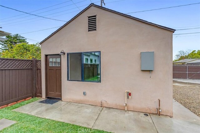 rear view of house with fence, a patio area, and stucco siding