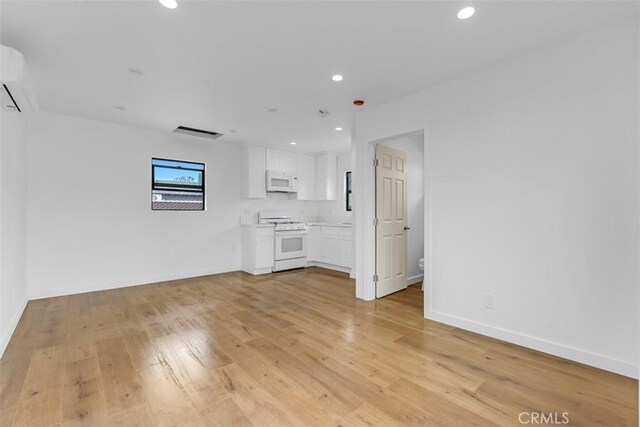 unfurnished living room featuring recessed lighting, baseboards, and light wood finished floors