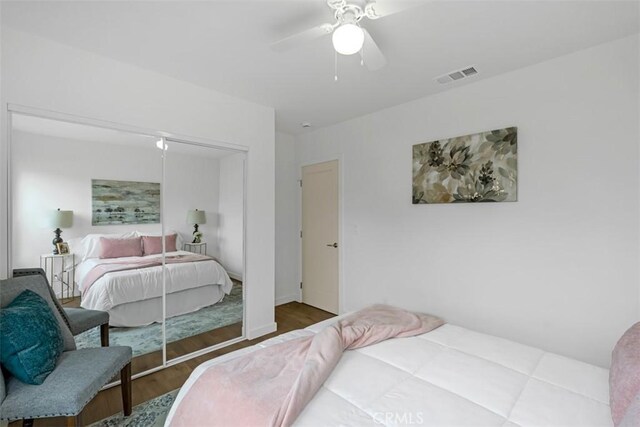 bedroom featuring ceiling fan, a closet, wood finished floors, and visible vents