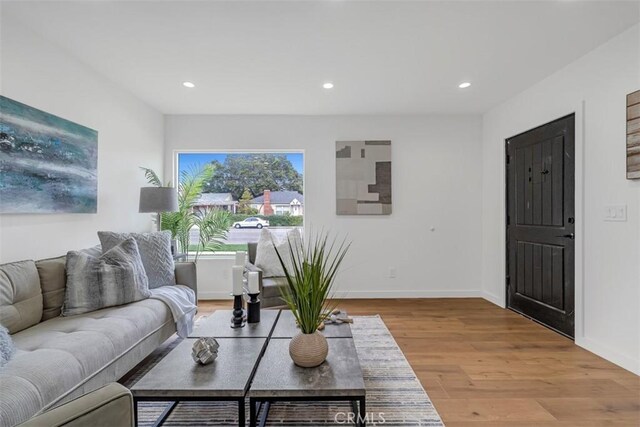 living area with baseboards, light wood-type flooring, and recessed lighting