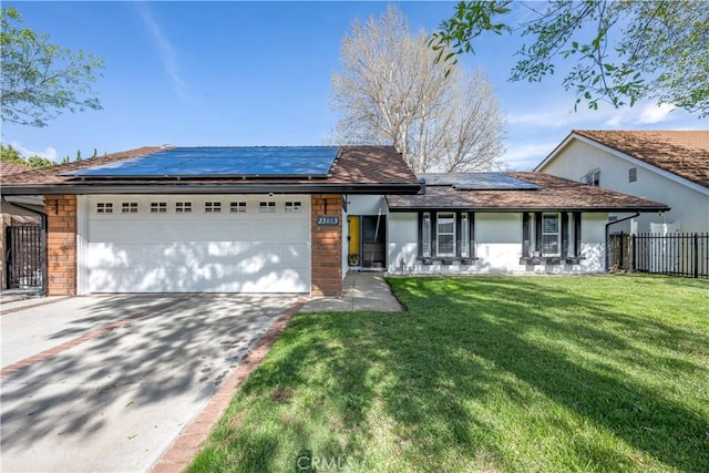 single story home with fence, an attached garage, concrete driveway, a front yard, and solar panels