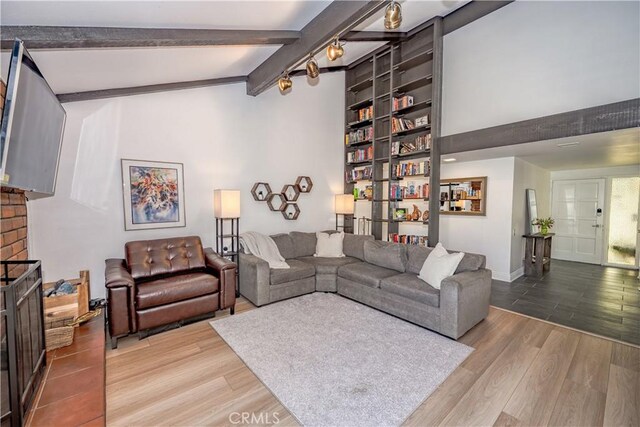 living room featuring baseboards, built in shelves, beam ceiling, a fireplace, and wood finished floors