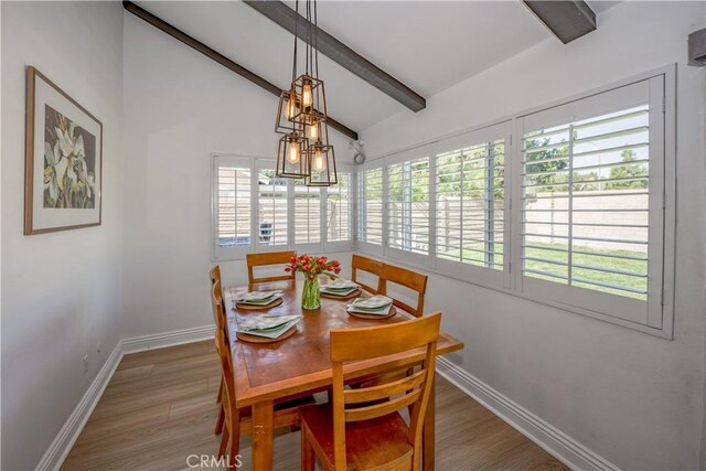 dining space featuring vaulted ceiling with beams, wood finished floors, and baseboards