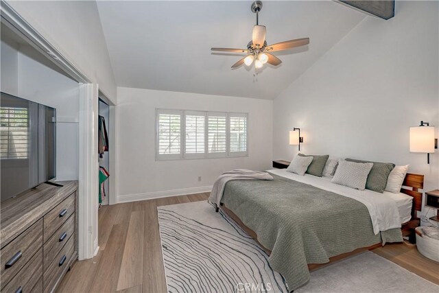 bedroom with baseboards, high vaulted ceiling, a ceiling fan, and light wood finished floors