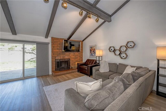 living area with rail lighting, a fireplace, wood finished floors, and beam ceiling