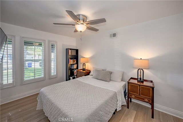 bedroom featuring baseboards, ceiling fan, visible vents, and wood finished floors