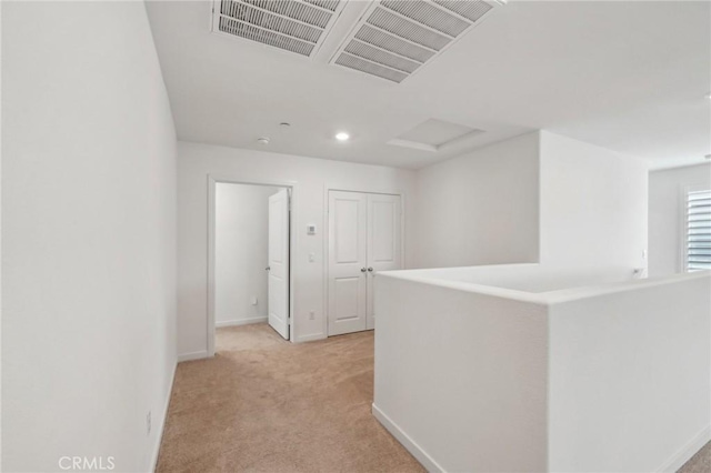 corridor with visible vents, baseboards, recessed lighting, attic access, and light colored carpet