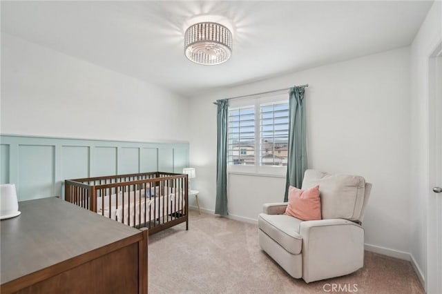 bedroom with light carpet, a decorative wall, and a wainscoted wall