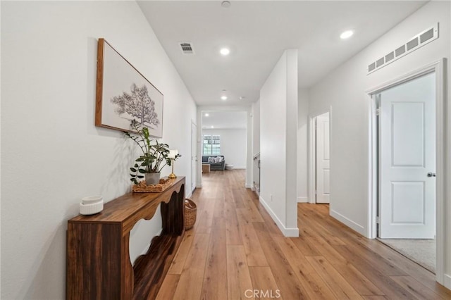 hallway with baseboards, visible vents, recessed lighting, and light wood finished floors