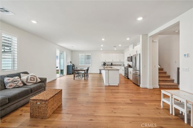living area featuring light wood-type flooring, recessed lighting, baseboards, and visible vents