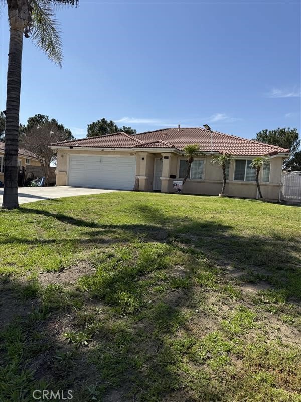 ranch-style house with stucco siding, concrete driveway, a front lawn, and an attached garage