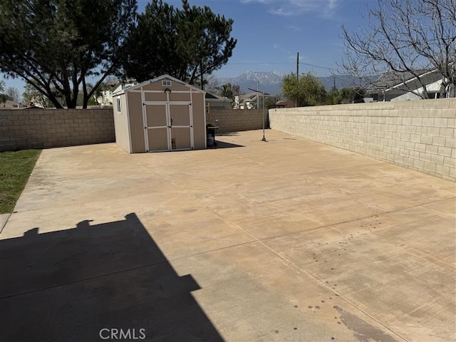 view of patio featuring an outbuilding, a mountain view, a fenced backyard, and a shed