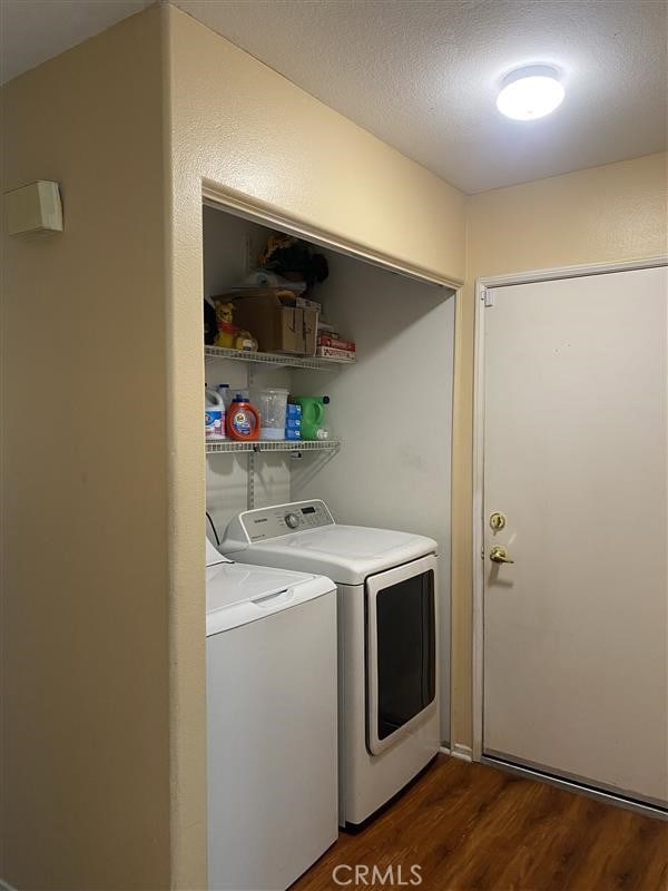 washroom with washing machine and dryer, laundry area, dark wood-type flooring, and a textured ceiling