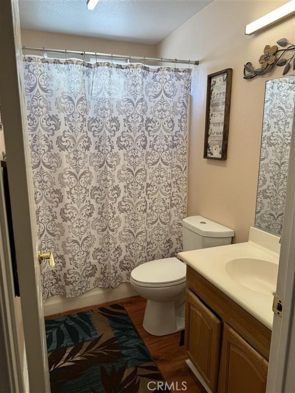 full bath featuring shower / bath combo, toilet, vanity, and wood finished floors