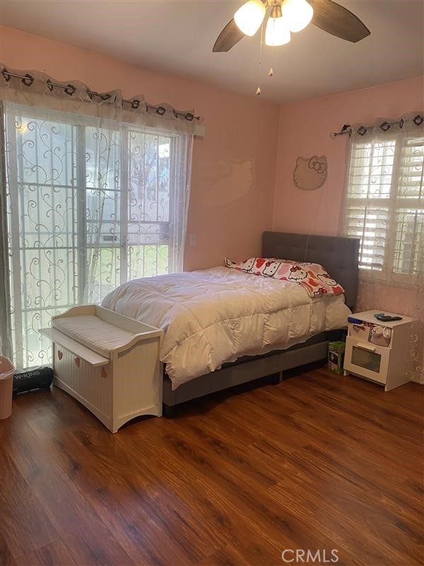bedroom with access to exterior, wood finished floors, and a ceiling fan