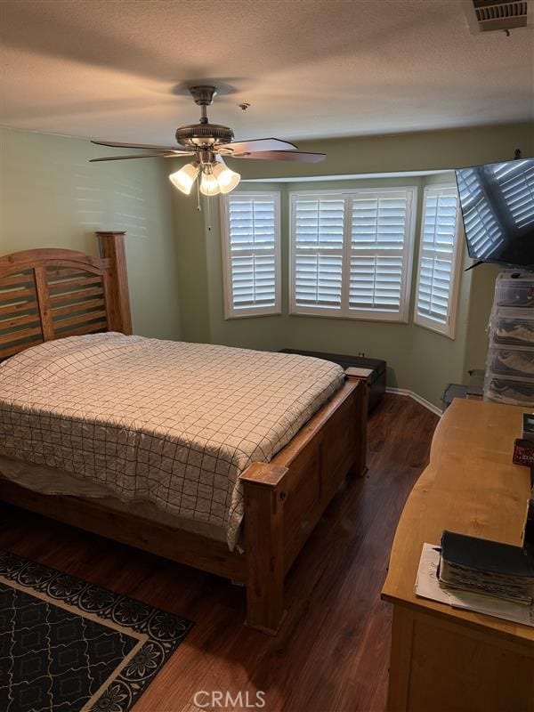bedroom featuring a textured ceiling, visible vents, a ceiling fan, and dark wood-style flooring