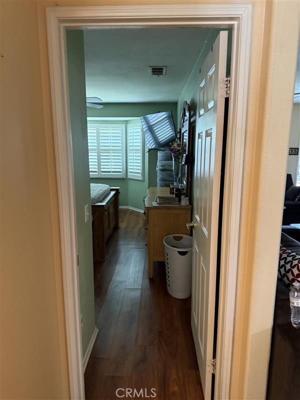 hall with dark wood-style floors, baseboards, and visible vents