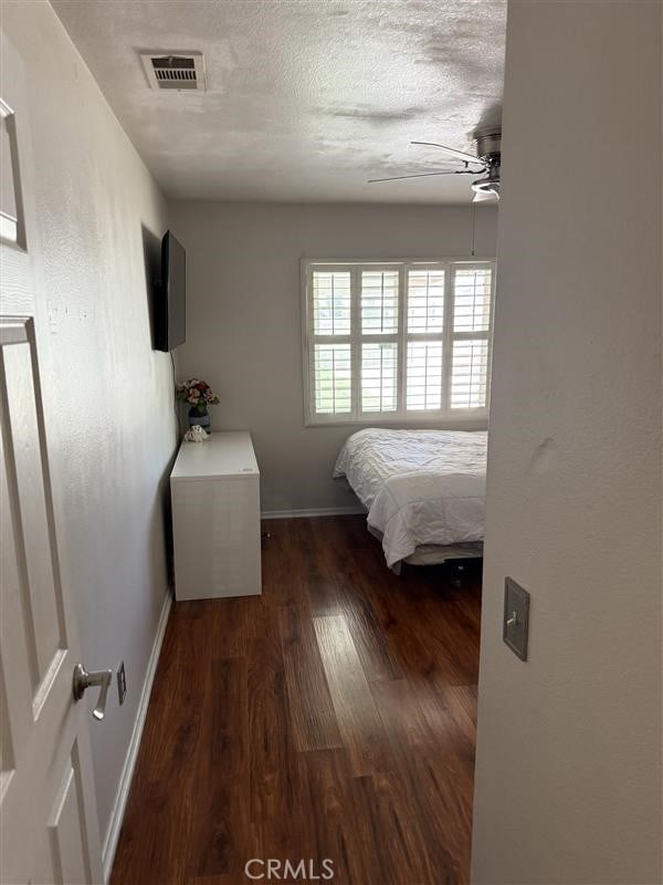 bedroom with a textured ceiling, baseboards, ceiling fan, and wood finished floors