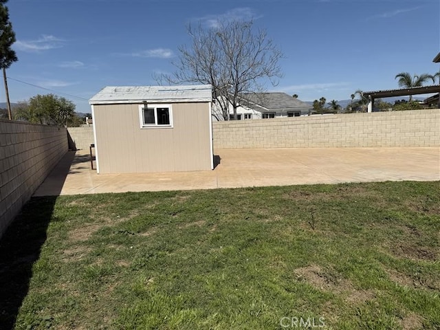 view of yard featuring a fenced backyard, an outbuilding, a shed, and a patio