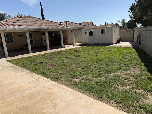 view of yard with an outdoor structure, a fenced backyard, and a patio area