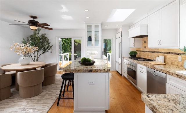 kitchen with a breakfast bar area, white cabinets, backsplash, and stainless steel appliances