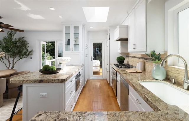 kitchen with white cabinetry, backsplash, a kitchen bar, and a sink