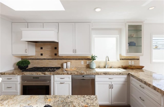 kitchen featuring white cabinetry, a sink, custom exhaust hood, and appliances with stainless steel finishes