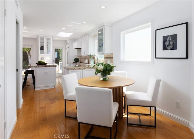 dining space featuring baseboards, recessed lighting, and light wood finished floors