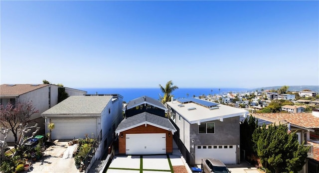view of front facade featuring stucco siding, a water view, a garage, and concrete driveway
