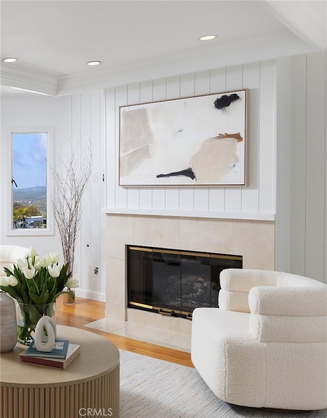 living area featuring a tiled fireplace, recessed lighting, crown molding, and wood finished floors