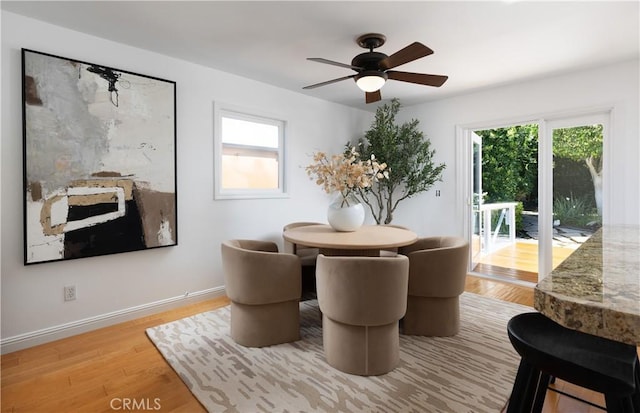 dining room with a ceiling fan, plenty of natural light, baseboards, and wood finished floors