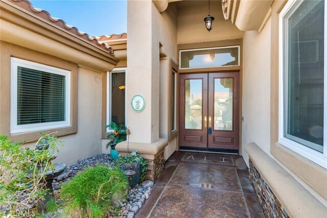 view of exterior entry featuring french doors, a tiled roof, and stucco siding