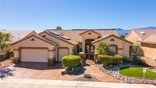 mediterranean / spanish-style home with a tiled roof, a garage, a gate, and stucco siding