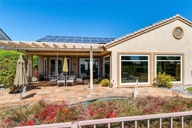 back of property featuring roof mounted solar panels, a tile roof, stucco siding, and a patio area