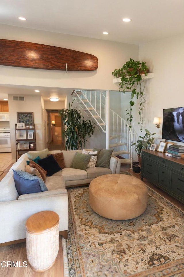 living room featuring recessed lighting, visible vents, stairway, and wood finished floors