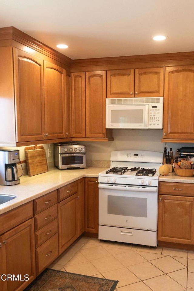 kitchen with light tile patterned flooring, light countertops, white appliances, recessed lighting, and brown cabinetry