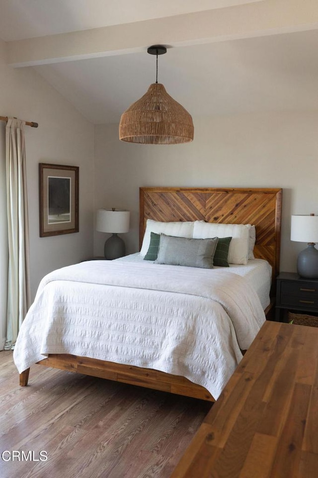 bedroom featuring vaulted ceiling with beams and wood finished floors