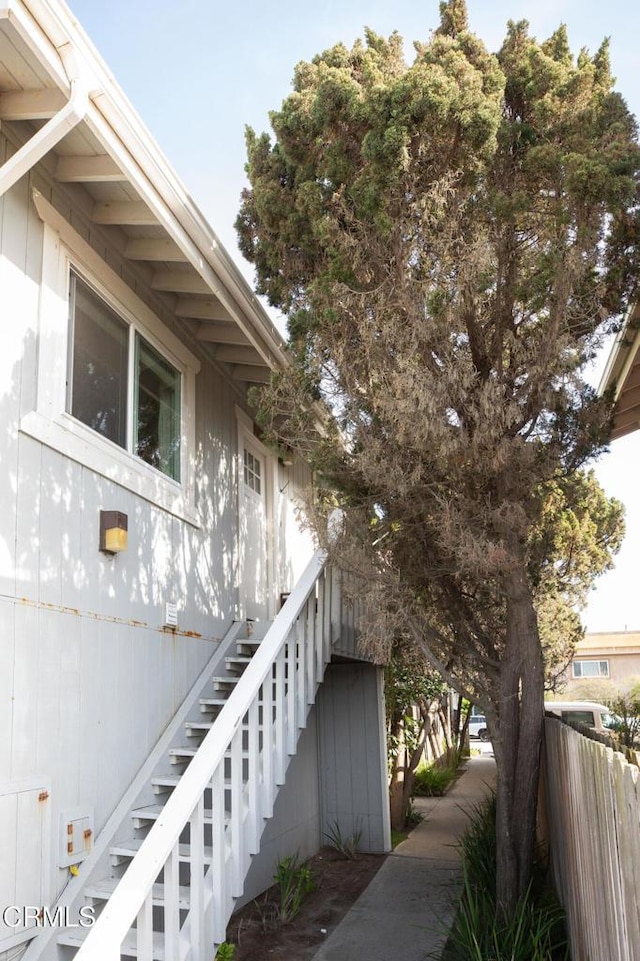 view of property exterior with fence and stairway