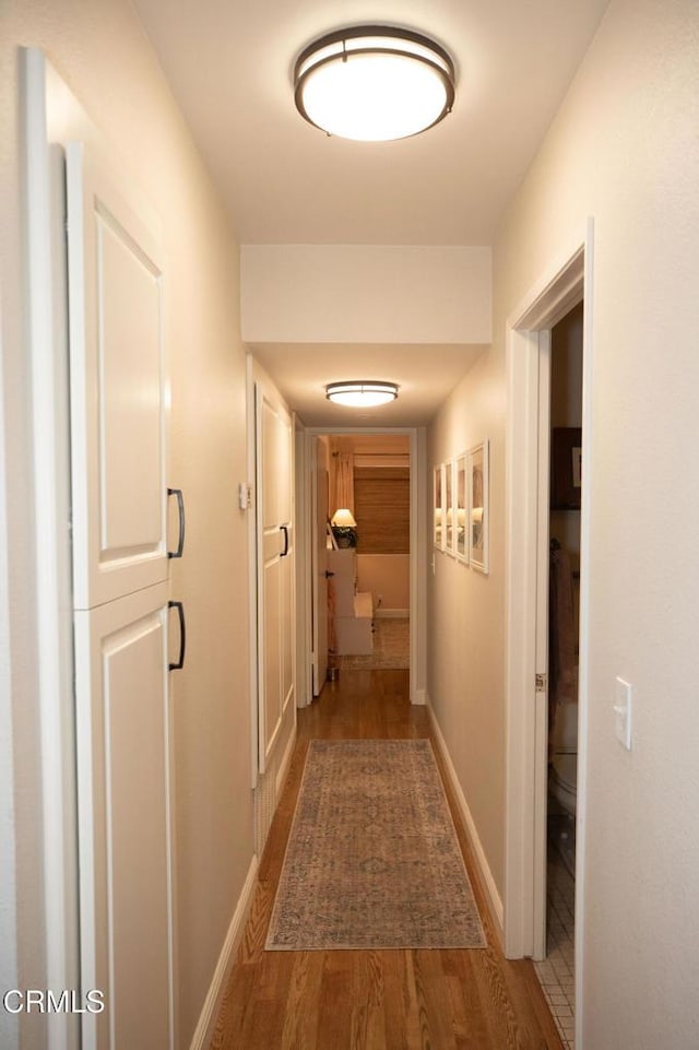 hall with baseboards and wood finished floors