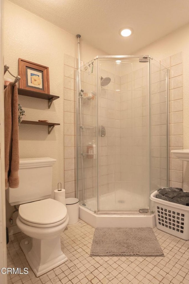 full bathroom with a stall shower, toilet, and tile patterned flooring