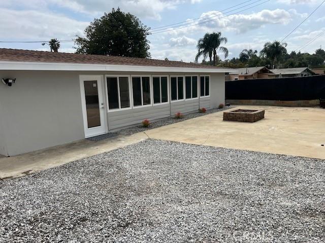 1197 Colony Dr, Pomona, CA 91766 - back of property featuring a patio area, stucco siding, fence, and an outdoor fire pit