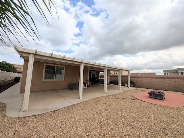 back of house featuring a patio, an outdoor fire pit, a fenced backyard, and central AC