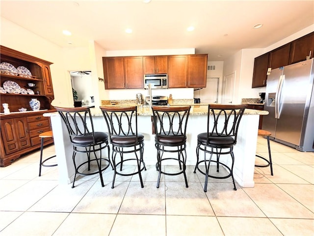 kitchen with a large island, light tile patterned floors, a breakfast bar area, visible vents, and appliances with stainless steel finishes