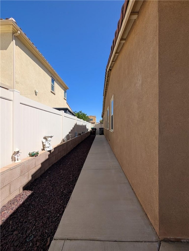 view of side of property with stucco siding, a patio area, and a fenced backyard