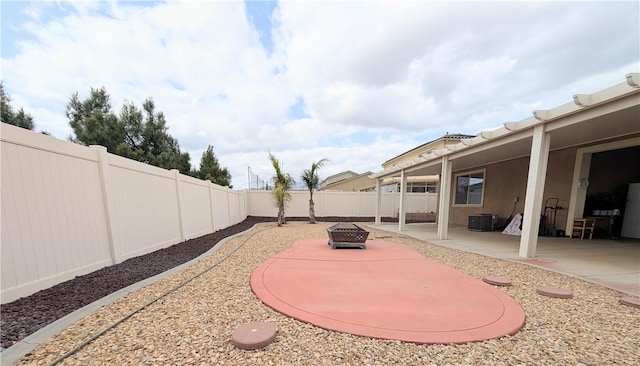 view of yard with a fire pit, a patio area, central AC, and a fenced backyard