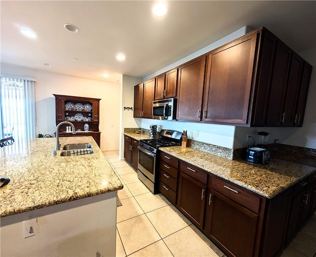 kitchen with light stone counters, light tile patterned floors, a sink, stainless steel appliances, and recessed lighting