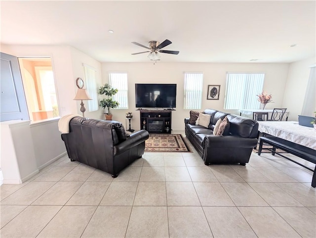 living room with baseboards, light tile patterned floors, ceiling fan, and plenty of natural light