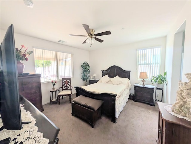 carpeted bedroom with a ceiling fan, multiple windows, baseboards, and visible vents